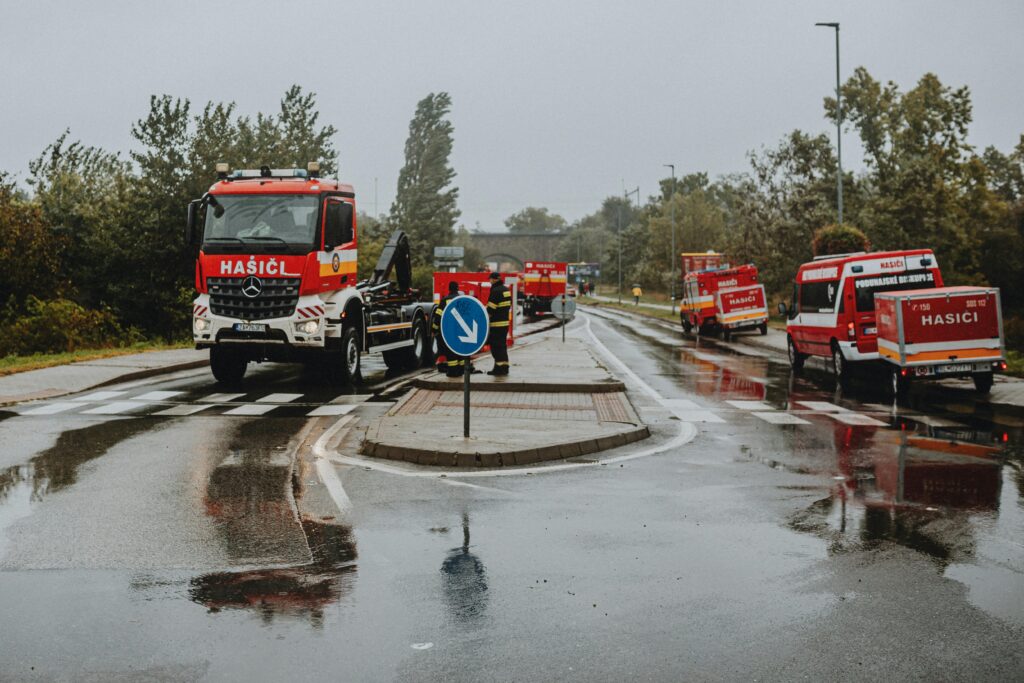 hasiči pomáhajúci pri záplavách - autá stojace na ulici v daždi